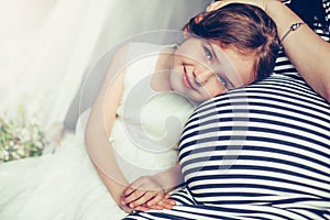 Pretty young baby girl smiling near pregnant mother