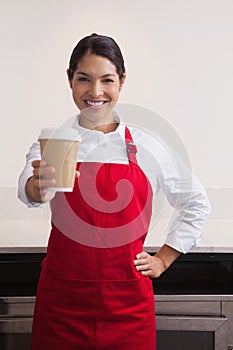 Pretty young barista offering cup of coffee to go