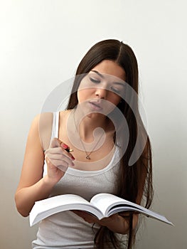 Pretty young beautiful woman sitting, thinks, writing, take notes, holding textbook notebook organizer in hand and pen