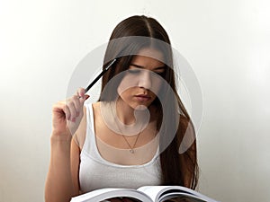 Pretty young beautiful woman sitting, thinks, writing, take notes, holding textbook notebook organizer in hand and pen