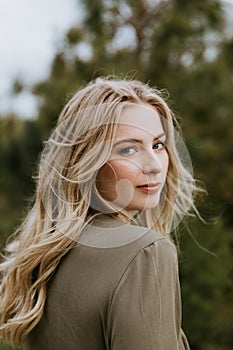 Pretty Young Beauty Woman Model with Gorgeous Long Blond Hair Blowing in the Wind Smiling for Portrait Shots Outside at the Park