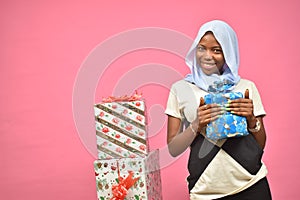 pretty young black woman holding a gift box and standing next to more gift boxes
