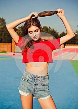 Pretty young blonde smiling woman outdoor lifestyle sunny portrait in sunglasses, red top and jeans shorts posing in summer on the