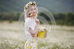 Pretty young blonde woman with camomiles in white blooming field. girl in camomile wreath