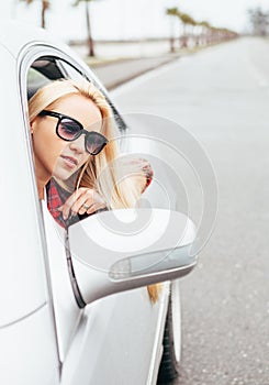 Pretty young blonde woman looks out from car window