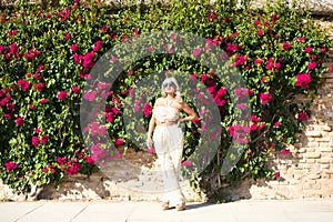 Pretty young blonde woman wearing sunglasses and dressed in embroidered trousers and crocheted top, enjoys sunny day. In the