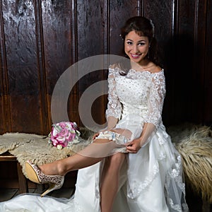 Pretty young bride playing with her garter