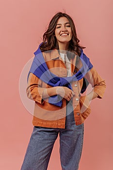 Pretty young brunette caucasian woman smiles looking at camera against pink background.