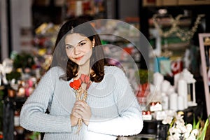 Pretty young brunette girl chooses decor for Valentine`s Day. Girl holding red hearts on a stick, festive decor