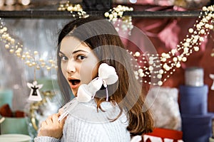 Pretty young brunette girl chooses decor for Valentine`s Day. Girl holding white hearts on a stick, festive decor