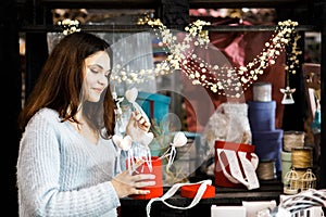 Pretty young brunette girl chooses decor for Valentine`s Day. Girl holding white hearts on a stick, festive decor