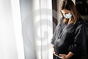 Pretty young brunette, pregnant woman with a medical face mask during covid-19 pandemic, pregnancy concept