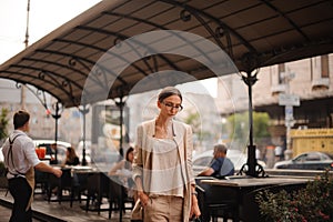 Pretty young brunette woman dressed casual posing outdoor with leather handbag