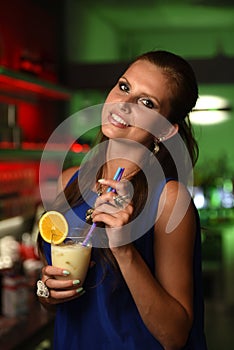 Pretty young brunette woman drinking cocktail in bar