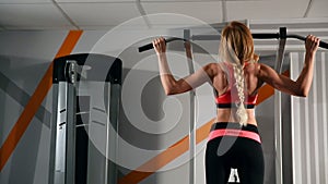 Pretty young brunette working out and doing some pull ups at a gym