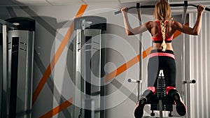 Pretty young brunette working out and doing some pull ups at a gym