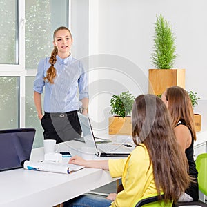 Pretty young business woman giving a presentation in conference or meeting setting. People and teamwork concept - happy