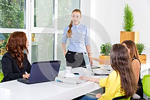 Pretty young business woman giving a presentation in conference or meeting setting. People and teamwork concept - happy