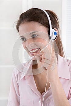 Pretty young business woman in rose blouse with headset.