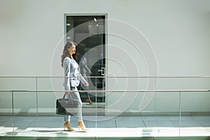 Pretty young business woman walking with briefcase in the office hallway