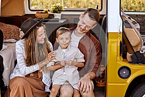 Pretty young Caucasian couple with child travelers on road trip on yellow retro van