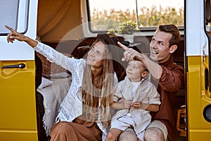 Pretty young Caucasian couple with child travelers on road trip on yellow retro van