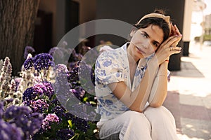 Pretty young caucasian girl posing looking at camera near flowers garden outdoor.