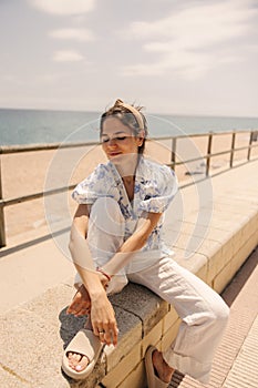 Pretty young caucasian girl spends time on beach, relaxing near sea in sunny weather.