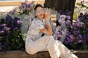 Pretty young caucasian girl with wavy hair relaxing in garden posing closed eyes.