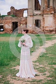 Pretty young caucasian redhead girl in a garden and outside with her wedding bouquet. Beautiful redhead bride