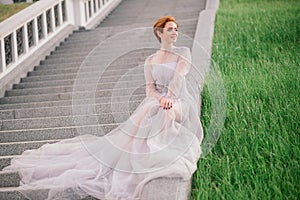 Pretty young caucasian redhead girl in a garden and outside with her wedding bouquet. Beautiful redhead bride