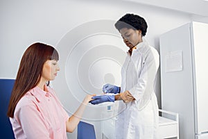 Pretty young Caucasian woman gives blood for analysis in modern light lab. Likable pleasant female African American