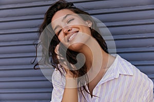 Pretty young caucasian woman looking into distance smiling corrects her hair.