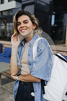 Pretty young caucasian woman smiles teeth at camera walking around city during day.