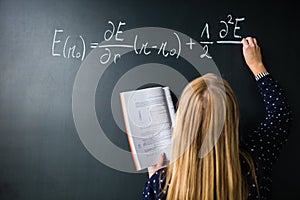 Pretty, young college student writing on the chalkboard