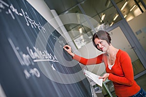 Pretty, young college student writing on the chalkboard