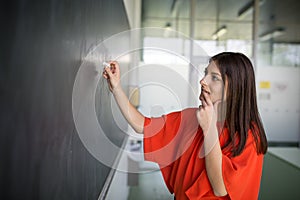 Pretty, young college student writing on the chalkboard/blackboard