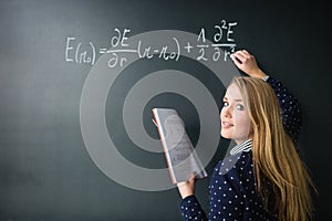 Pretty, young college student writing on the chalkboard/blackboard