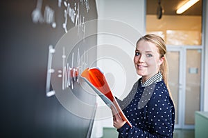 Pretty, young college student writing on the chalkboard/blackboard