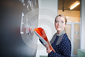 Pretty, young college student writing on the chalkboard/blackboard