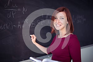 Pretty, young college student writing on the chalkboard/blackboard