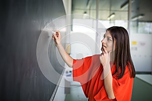 Pretty, young college student/young teacher writing on the chalkboard