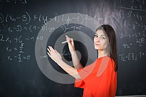 Pretty, young college student/young teacher writing on the chalkboard