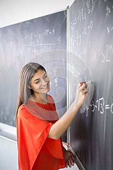 Pretty, young college student/young teacher writing on the chalkboard