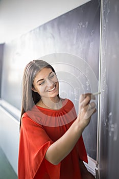 Pretty, young college student/young teacher writing on the chalkboard