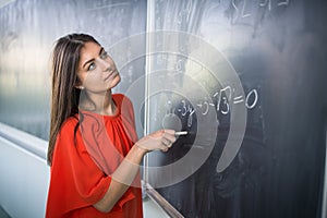 Pretty, young college student/young teacher writing on the chalkboard