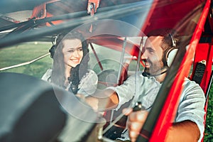 Pretty young couple sitting in airplane cabin with aviation headset