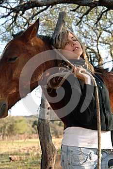 Pretty young cowgirl with a horse