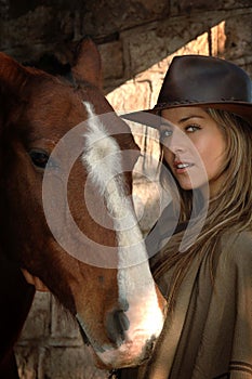 Pretty young cowgirl with a horse