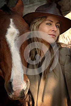 Pretty young cowgirl with a horse